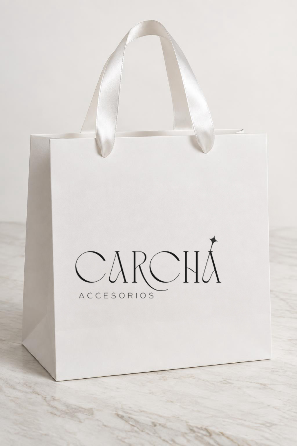 Bolsita de regalo blanca Carchá con el logo sobre piedra blanca